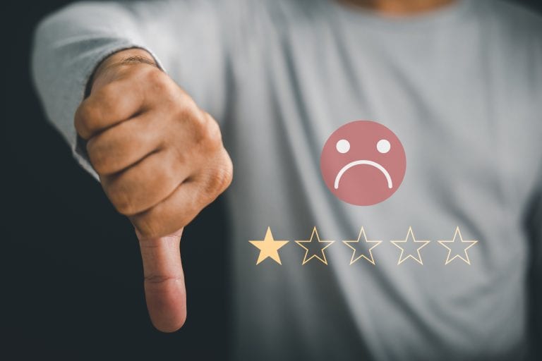 Main avec le pouce vers le bas accompagnée d'un emoji insatisfait et une seule étoile, symbole d'avis négatif